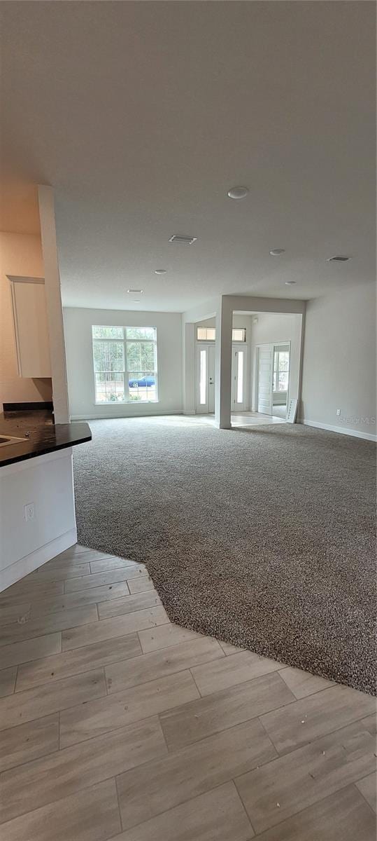 spare room featuring light carpet, baseboards, and light wood-style floors