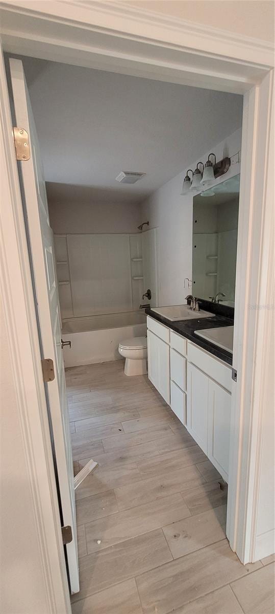 full bathroom featuring visible vents, toilet, wood finished floors, bathtub / shower combination, and vanity