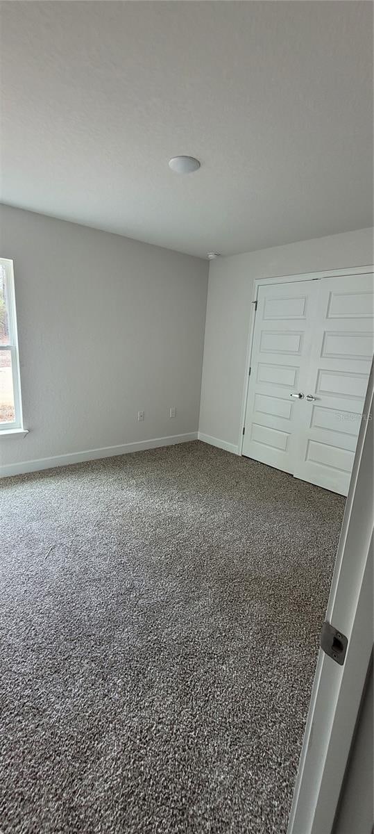 unfurnished bedroom with carpet flooring and baseboards