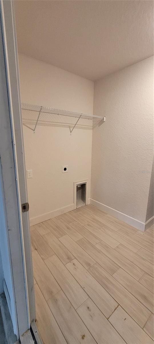 clothes washing area with light wood-style flooring, laundry area, electric dryer hookup, and baseboards