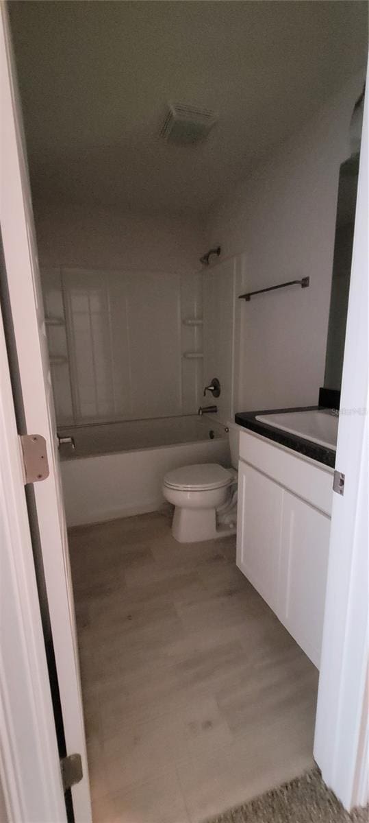 bathroom featuring wood finished floors, shower / bath combination, vanity, and toilet