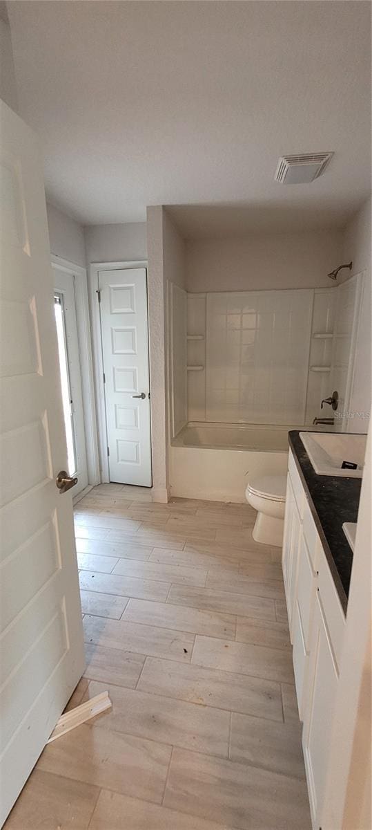 bathroom with visible vents, toilet, wood finished floors, tub / shower combination, and vanity