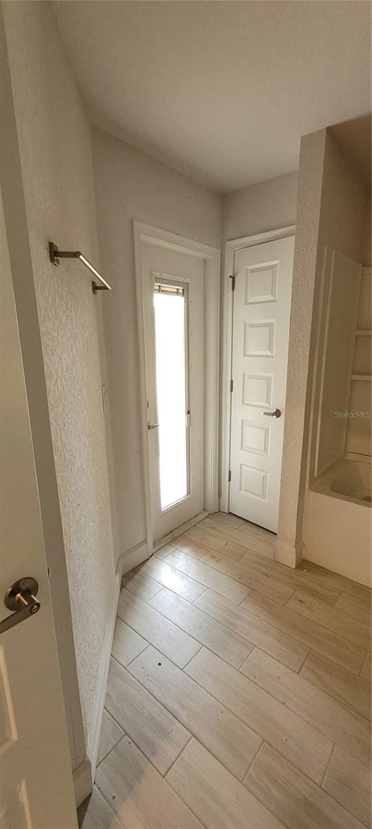 entryway featuring light wood-style flooring and a textured wall