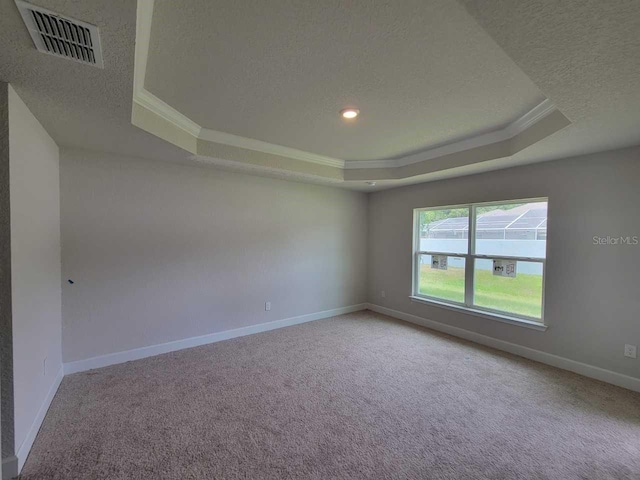 spare room featuring baseboards, visible vents, a textured ceiling, and a tray ceiling