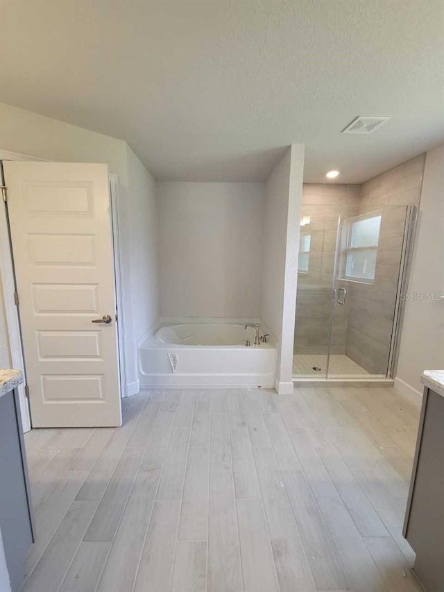 full bath featuring a bath, a shower stall, vanity, and wood finished floors