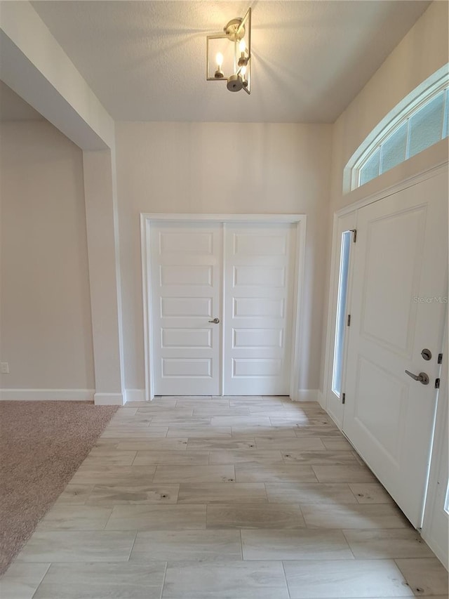 foyer entrance featuring wood finish floors, a textured ceiling, and baseboards