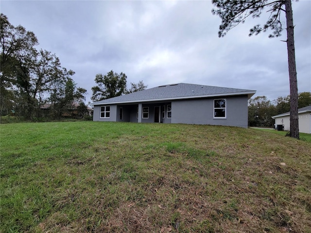 back of house featuring a lawn and stucco siding