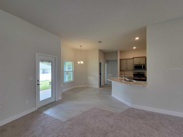 kitchen with visible vents, baseboards, light carpet, appliances with stainless steel finishes, and a sink