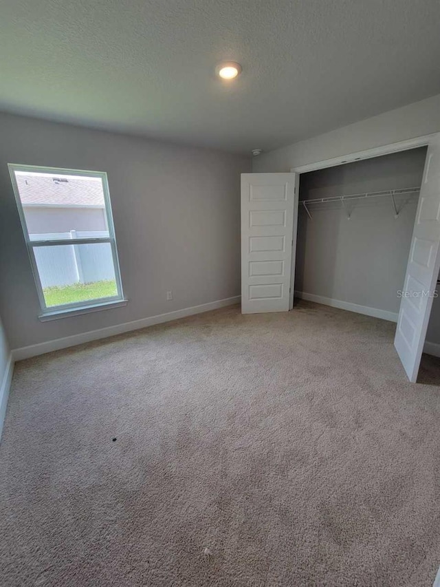 11610 SW 59th Ter, Ocala, FL 34476 - unfurnished bedroom with carpet flooring, a textured ceiling, and a closet