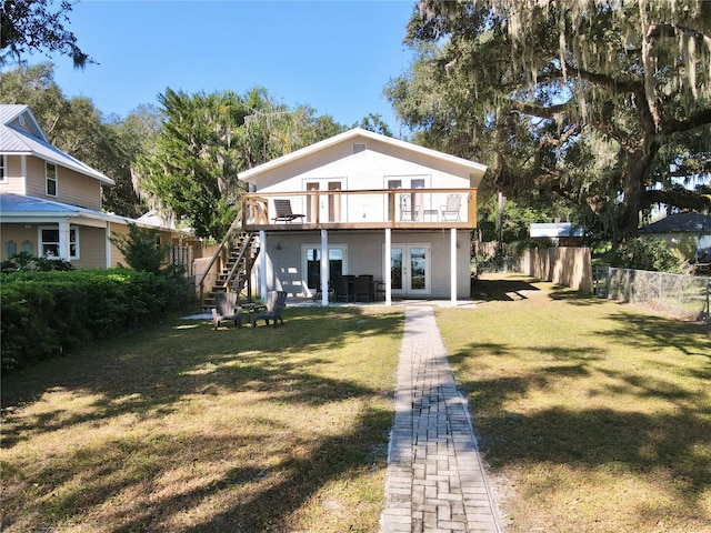 view of front facade featuring a patio area, a balcony, a front yard, and french doors