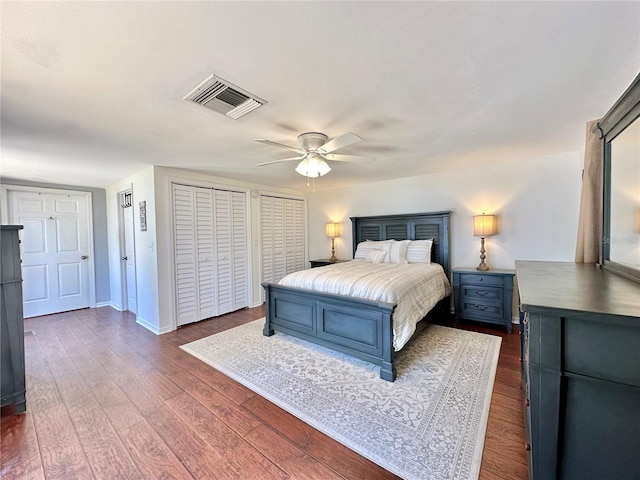 bedroom featuring multiple closets, ceiling fan, and dark hardwood / wood-style flooring