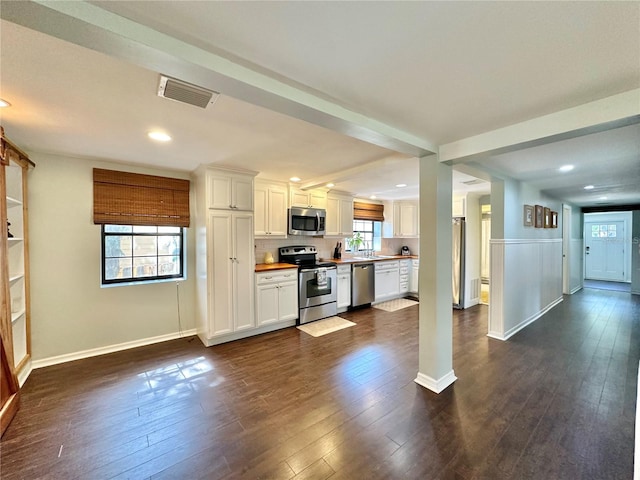 kitchen with appliances with stainless steel finishes, dark hardwood / wood-style floors, and white cabinetry