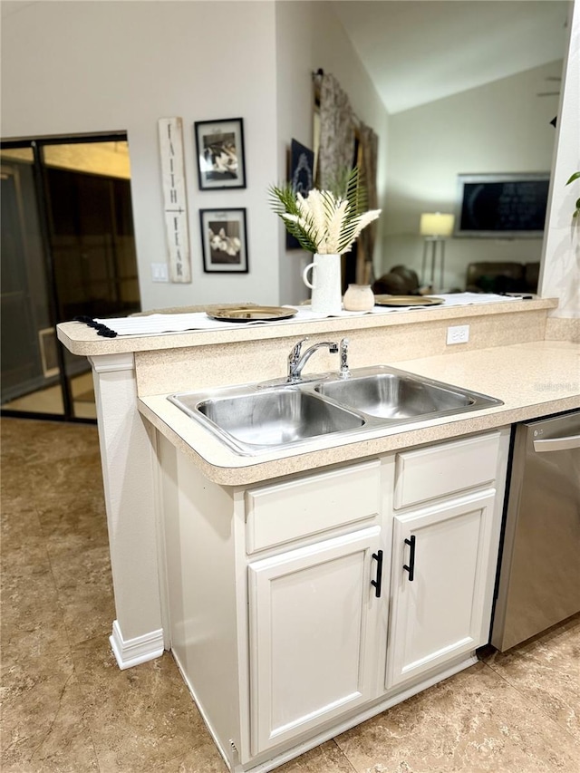 kitchen with kitchen peninsula, vaulted ceiling, sink, dishwasher, and white cabinetry