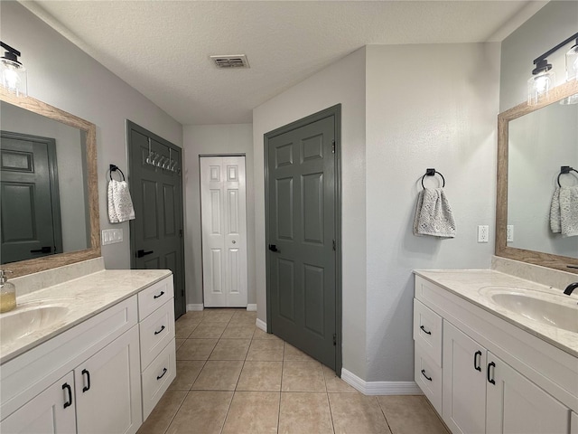 bathroom with tile patterned flooring, vanity, and a textured ceiling