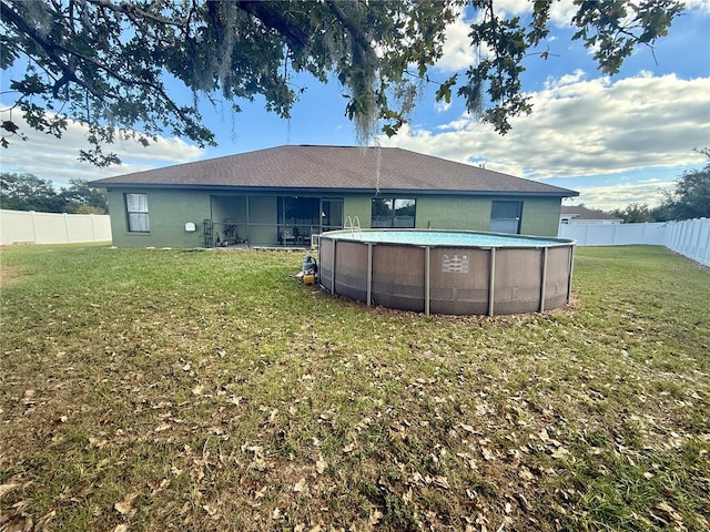 back of property with a fenced in pool and a yard