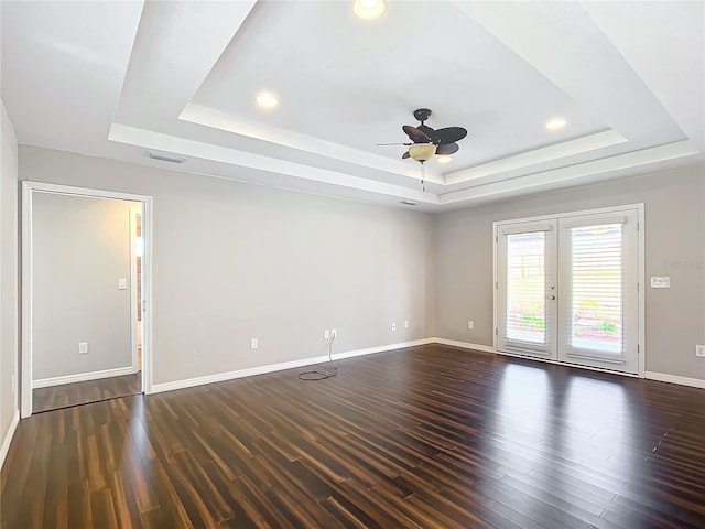 unfurnished room featuring a raised ceiling, dark hardwood / wood-style flooring, and french doors