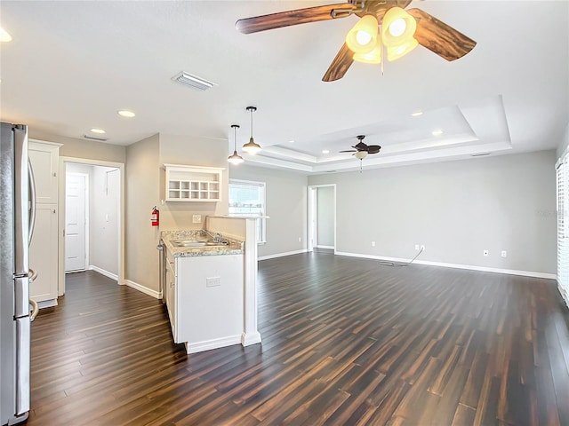 kitchen featuring stainless steel fridge, dark hardwood / wood-style flooring, white cabinetry, and a raised ceiling