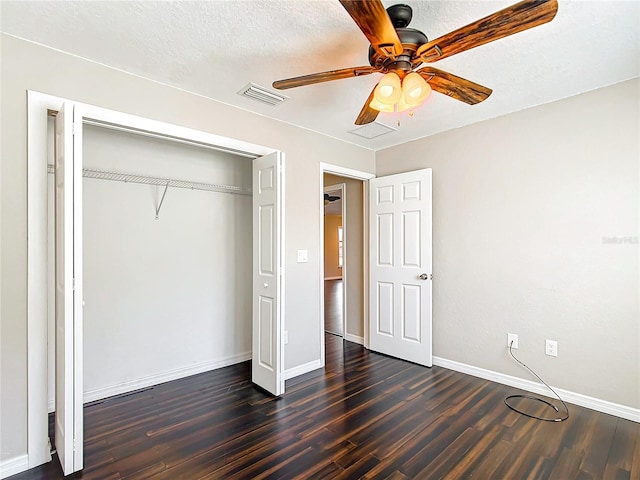 unfurnished bedroom featuring ceiling fan, a closet, dark wood-type flooring, and a textured ceiling