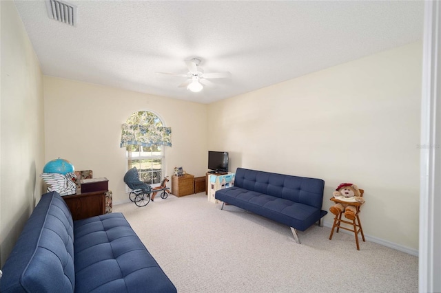 carpeted living room with a textured ceiling and ceiling fan