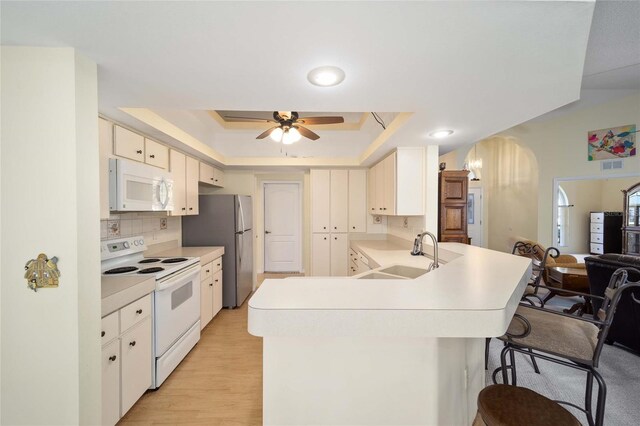 5336 SW 109th Place Rd, Ocala, FL 34476 - kitchen featuring white appliances, arched walkways, a raised ceiling, a sink, and light countertops
