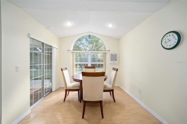 dining room with light hardwood / wood-style flooring and vaulted ceiling