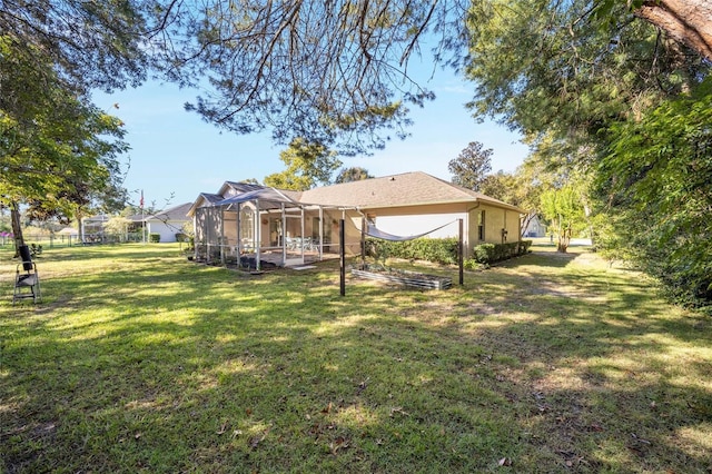 back of house featuring glass enclosure and a yard