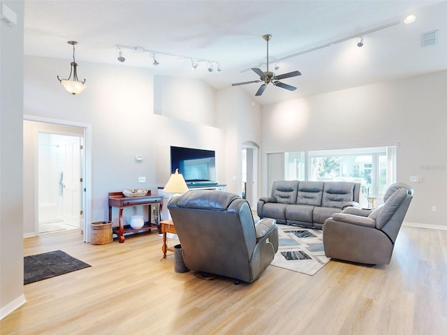 living room with ceiling fan, light hardwood / wood-style floors, rail lighting, and high vaulted ceiling