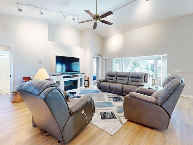 living room with ceiling fan, light hardwood / wood-style floors, a fireplace, and high vaulted ceiling