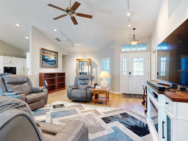 living room featuring ceiling fan, light hardwood / wood-style flooring, rail lighting, and vaulted ceiling