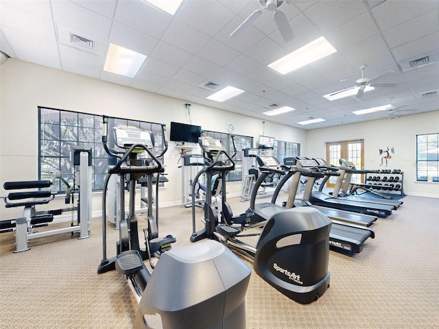 exercise room with ceiling fan, a drop ceiling, and light carpet