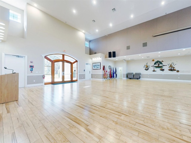 workout room featuring plenty of natural light, light wood-type flooring, and a towering ceiling