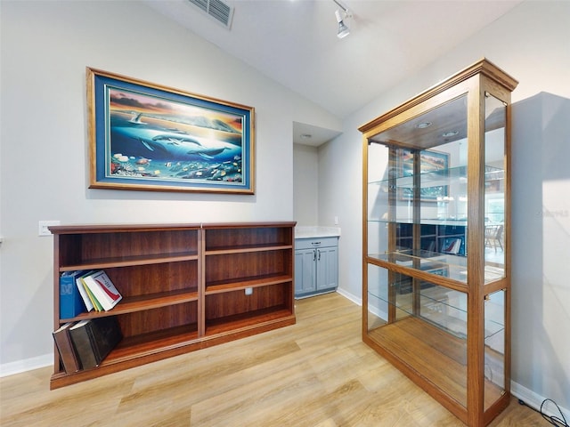 interior space with light wood-type flooring, rail lighting, and lofted ceiling