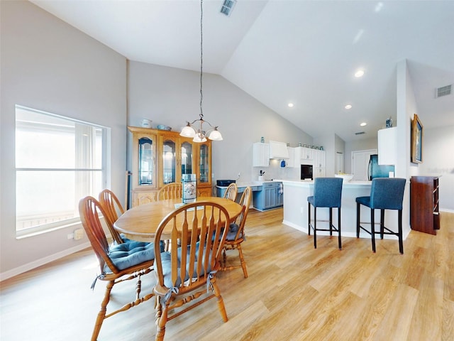 dining room with a notable chandelier, light hardwood / wood-style floors, and high vaulted ceiling