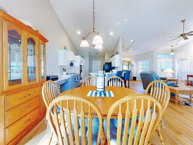 dining space with ceiling fan with notable chandelier, light hardwood / wood-style floors, and lofted ceiling