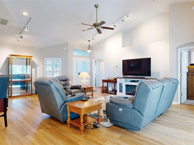 living room with ceiling fan, rail lighting, high vaulted ceiling, and light wood-type flooring