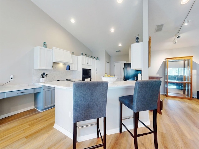 kitchen featuring kitchen peninsula, white cabinetry, lofted ceiling, and black appliances