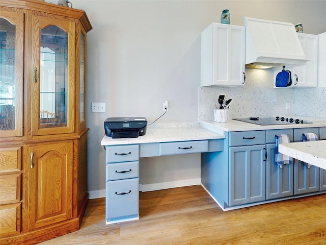 kitchen with white cabinets, black electric stovetop, custom range hood, and light hardwood / wood-style flooring