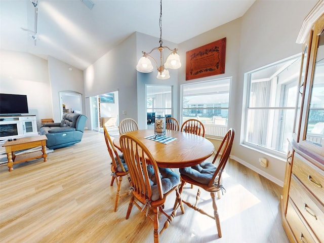 dining area featuring track lighting, light hardwood / wood-style floors, high vaulted ceiling, and a chandelier