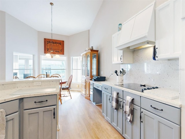 kitchen with custom range hood, gray cabinets, light hardwood / wood-style flooring, and hanging light fixtures