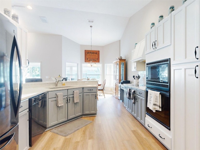 kitchen featuring gray cabinetry, sink, light hardwood / wood-style floors, decorative light fixtures, and black appliances