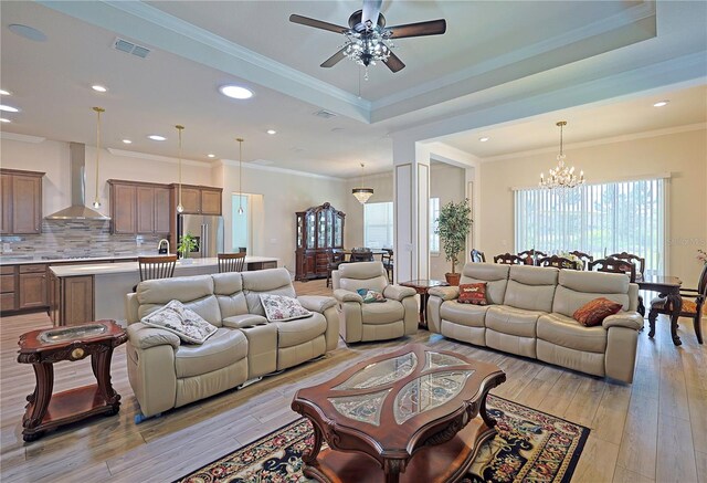 living room with crown molding, light hardwood / wood-style flooring, and ceiling fan with notable chandelier