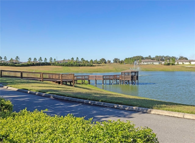 dock area with a lawn and a water view