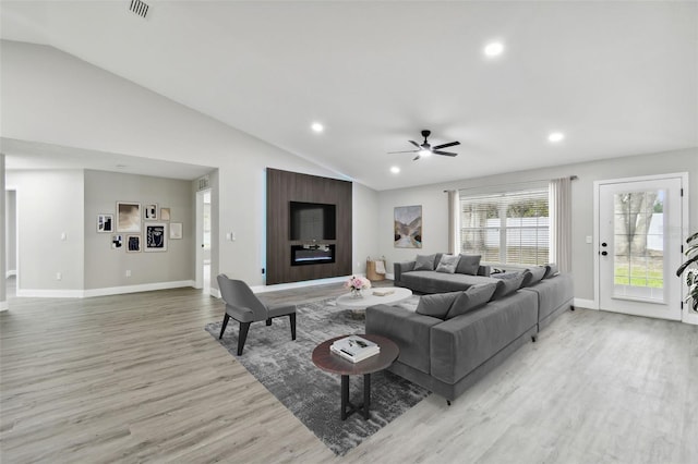 living room featuring ceiling fan, light hardwood / wood-style floors, and lofted ceiling