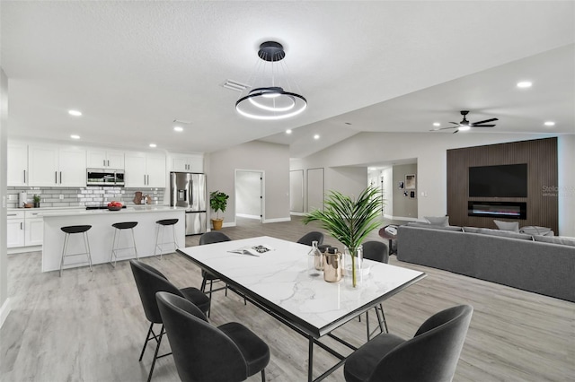 dining space featuring light wood-type flooring, vaulted ceiling, and ceiling fan