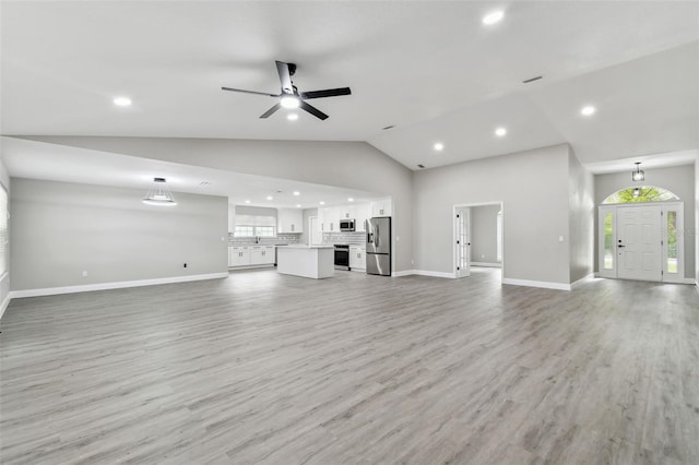 unfurnished living room featuring ceiling fan, light hardwood / wood-style floors, and vaulted ceiling