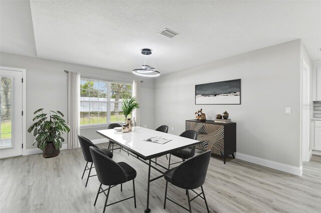 dining area featuring a textured ceiling and light hardwood / wood-style flooring