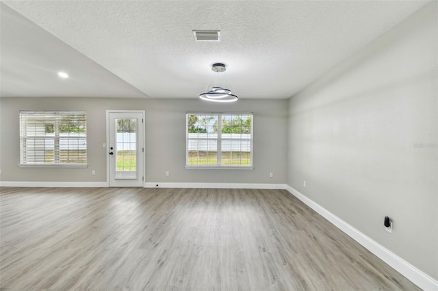 spare room with light wood-type flooring and a textured ceiling