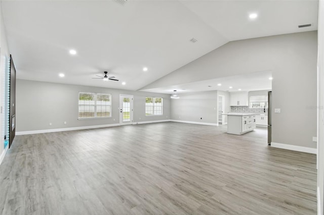 unfurnished living room featuring ceiling fan, light hardwood / wood-style floors, and vaulted ceiling