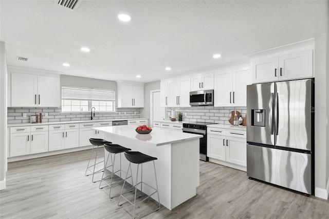 kitchen with white cabinets, a center island, a kitchen bar, and stainless steel appliances