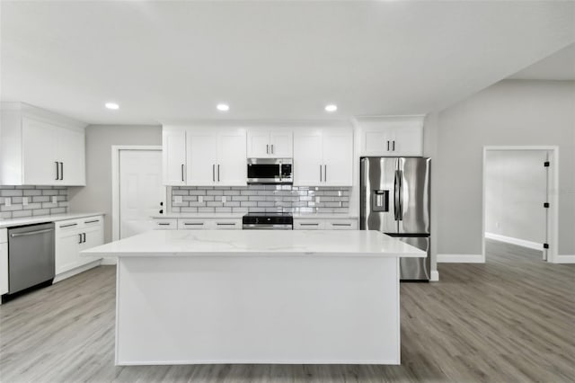 kitchen with light stone counters, white cabinets, stainless steel appliances, and light hardwood / wood-style floors